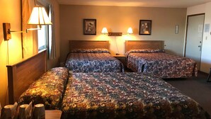 Une chambre d’hôtel avec deux lits, une tête de lit en bois, une table de chevet et une lampe.