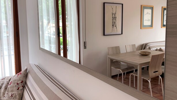 Quarto com uma janela grande, mesa de jantar com cadeiras e quadros na parede.