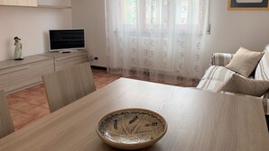 Uma sala de estar moderna com uma mesa de jantar, um sofá, uma televisão e uma tigela decorativa.