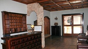 A reception area with a wooden desk, stone archway, and a tiled floor. - Hotel El Seto (Motilla del Palancar)