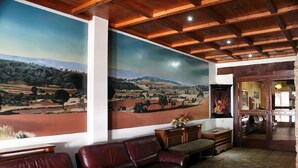 A room with a large landscape painting, leather sofas, and a wooden ceiling. - Hotel El Seto (Motilla del Palancar)
