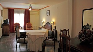 A hotel room with a bed, a desk, a chair, a small table, a lamp, a mirror, and a potted plant. - Hotel El Seto (Motilla del Palancar)