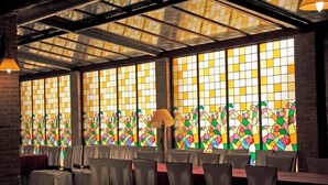 A restaurant with large stained glass windows, tables with chairs, and hanging lamps. - Hotel El Seto (Motilla del Palancar)