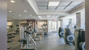 A gym with various exercise machines, a treadmill, and a mirrored wall. - Downtown Luxury Suites (Jersey City)