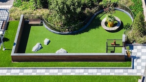 A landscaped garden with a rectangular lawn, a circular planter, and a wooden bench. - Downtown Luxury Suites (Jersey City)