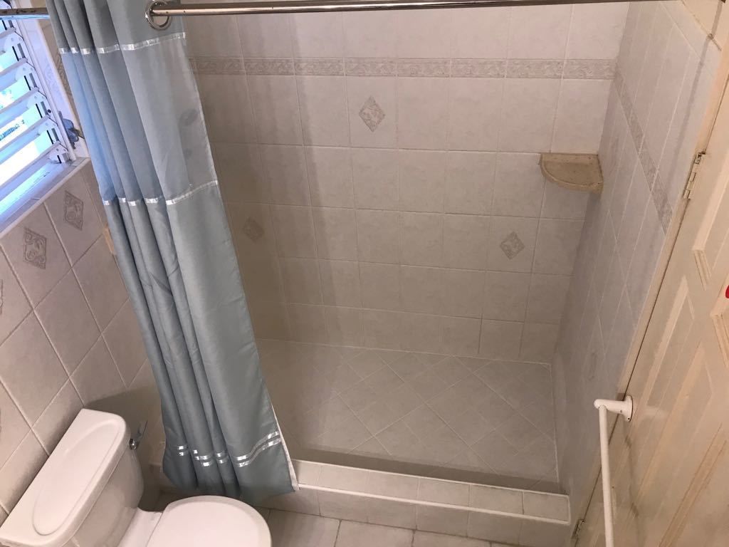 Et bruseområde med glasdør, toilet og bruseforhæng.