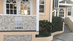 Un edificio residencial con fachada color beige, ventanas con marcos blancos y una pared de acento de piedra.