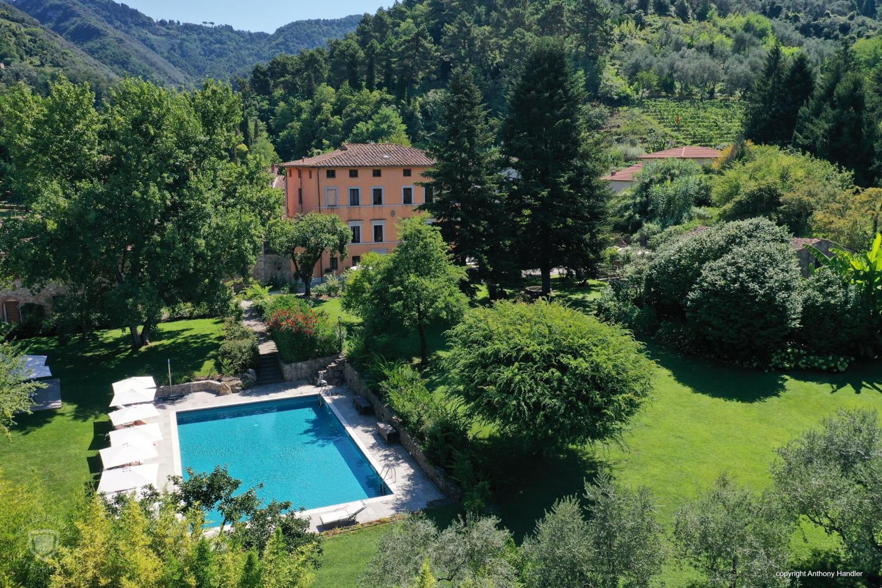 A villa with a swimming pool surrounded by lush greenery and hills.