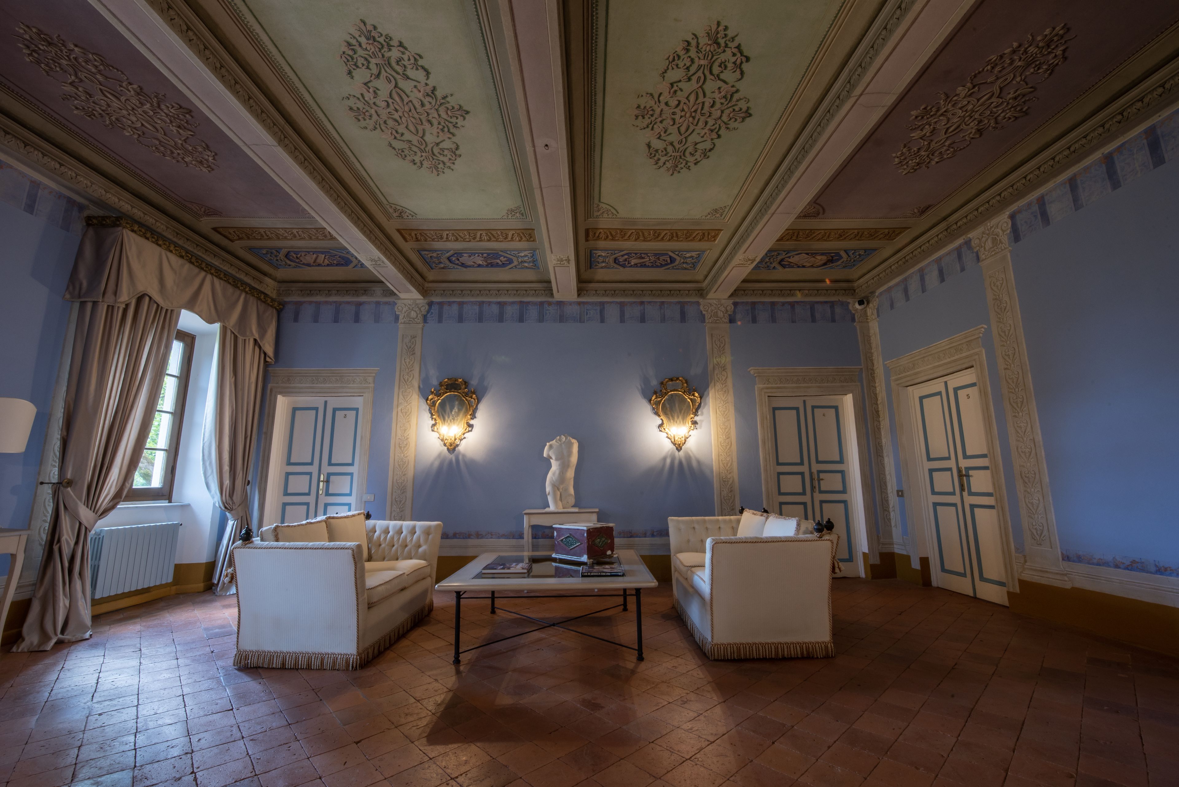 A room with a fireplace, two sofas, a coffee table, and a statue.