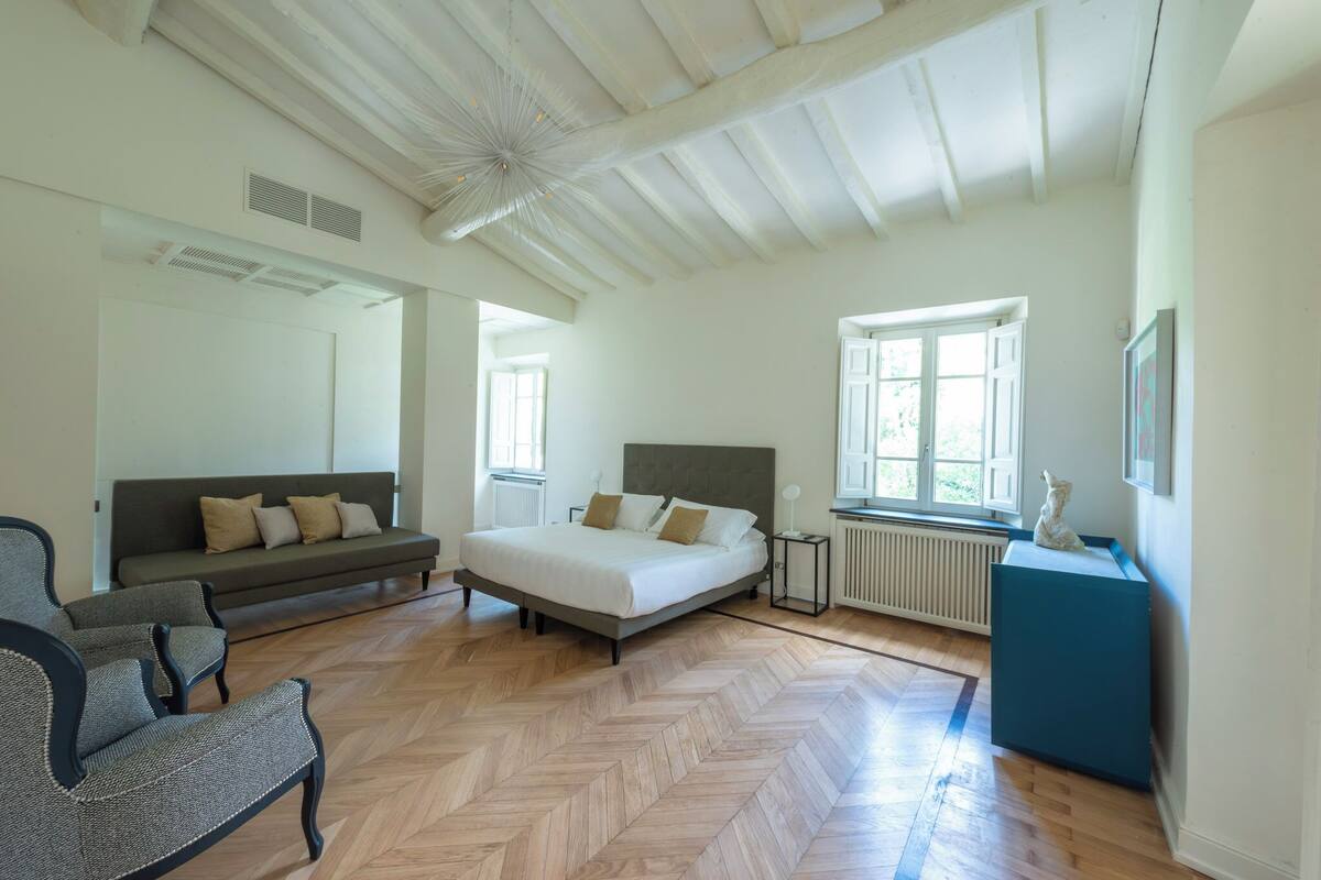 A spacious bedroom with a large bed, a sofa, and a chair.