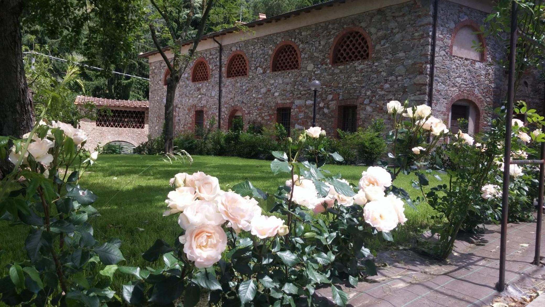 A stone building with arched windows and a garden with roses.