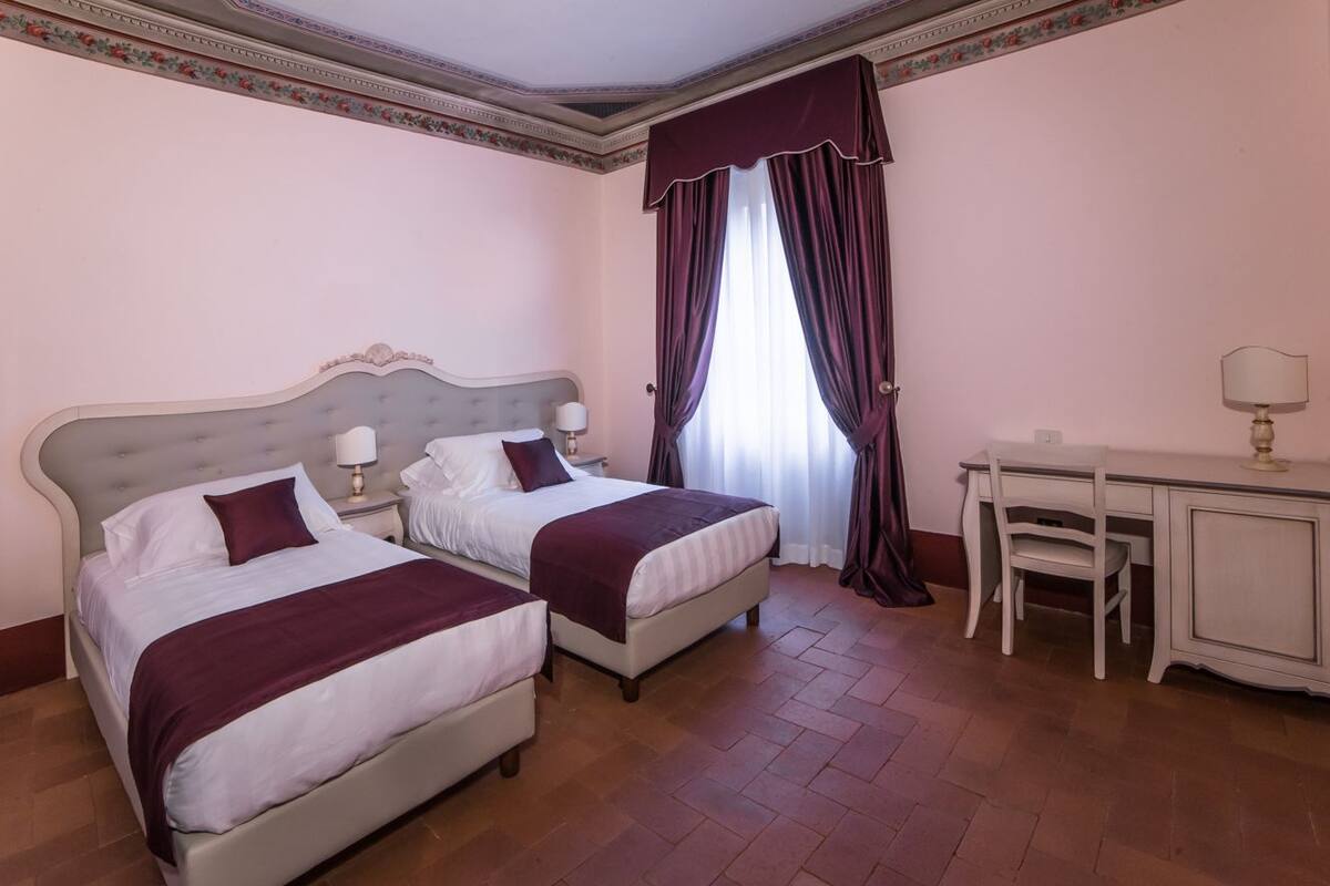 A hotel room with two beds, a desk, and a chair.