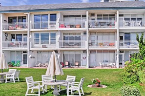 Un edificio residencial de varios pisos con balcones, mobiliario exterior y un césped bien cuidado.