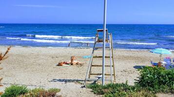 A beach with a wooden ladder, a towel, and a beach umbrella.