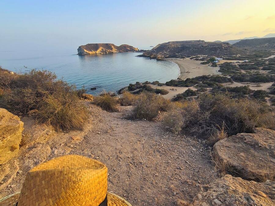 A straw hat on a wooden surface with a coastal landscape in the background.