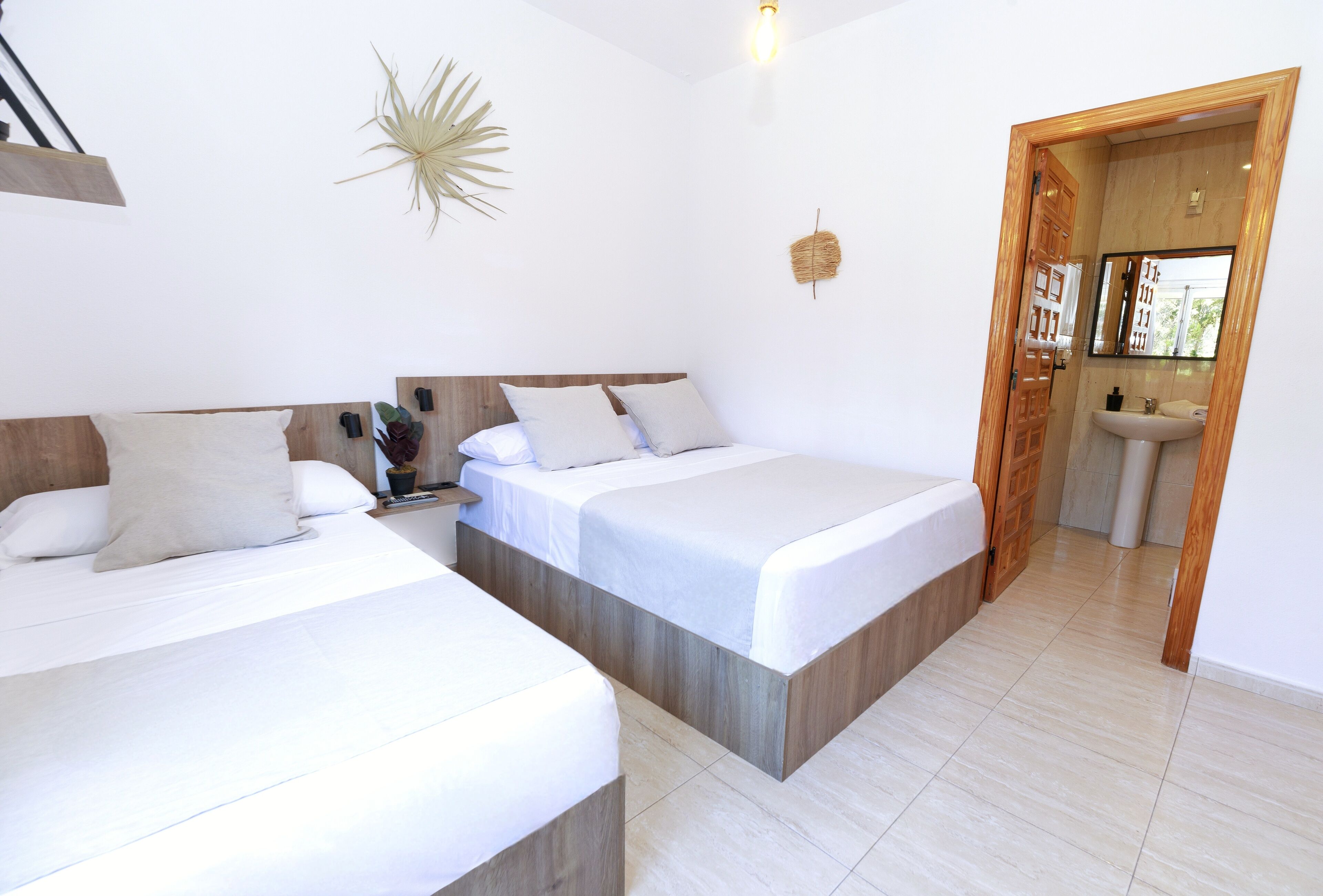 Een hotelkamer met twee bedden, een houten hoofdbord, een wandlamp en een badkamer zichtbaar door een open deur.