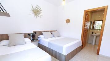 Een hotelkamer met twee bedden, een houten hoofdbord, een wandlamp en een badkamer zichtbaar door een open deur.