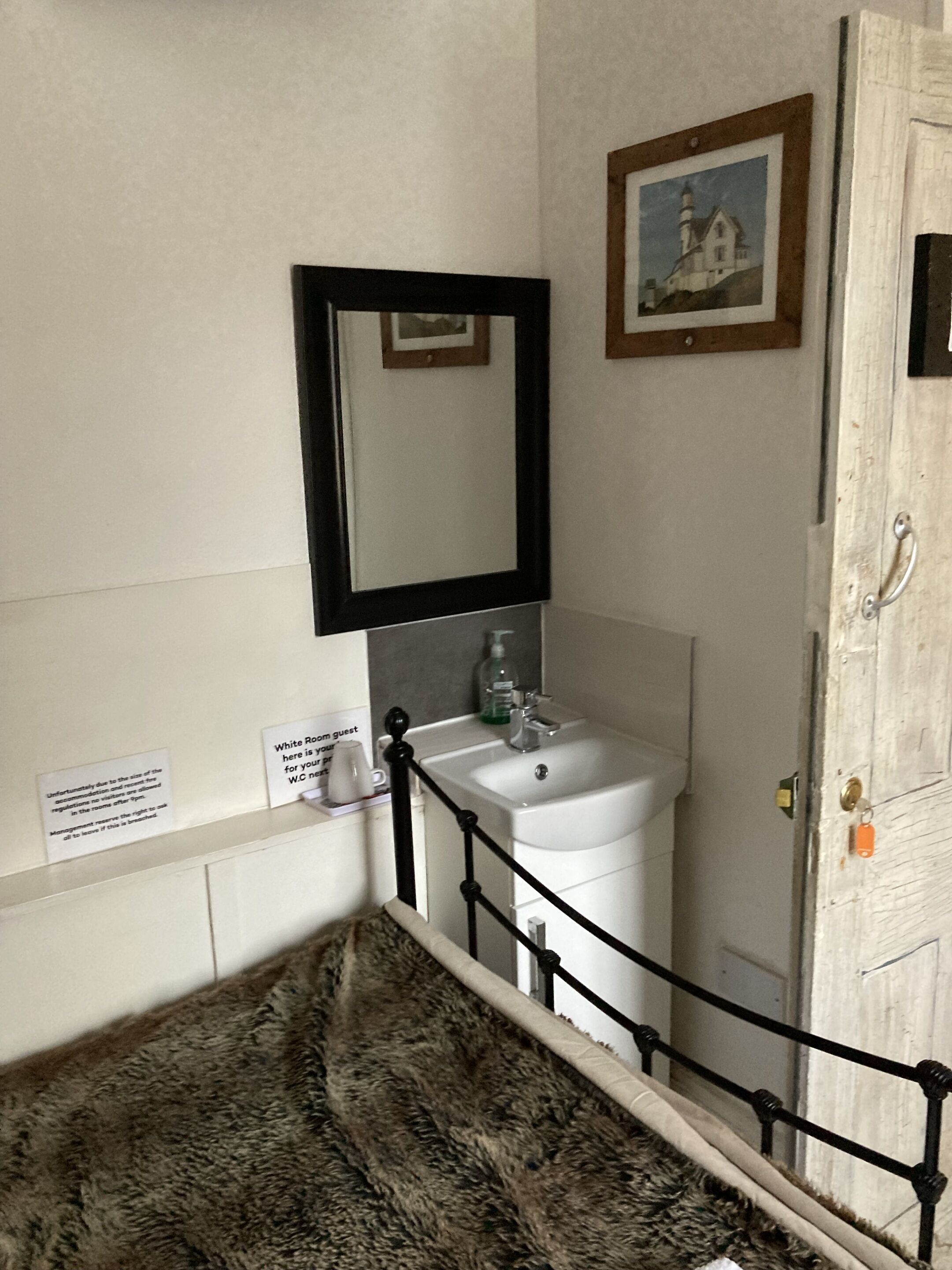 A bathroom with a sink, mirror, and a framed picture on the wall.