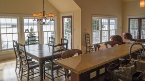 A spacious kitchen with a large island, multiple windows, and a view of a body of water. - LUXURY HOME WITH GUEST HOUSE ON ACADIAN ISLAND ESTATE (Monastery)