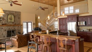 A spacious kitchen with a central island, wooden ceiling, and a stone fireplace. - LUXURY HOME WITH GUEST HOUSE ON ACADIAN ISLAND ESTATE (Monastery)