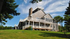 A large, two-story house with a wrap-around porch, a chimney, and a deck. - LUXURY HOME WITH GUEST HOUSE ON ACADIAN ISLAND ESTATE (Monastery)
