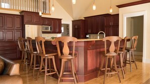 A kitchen with dark wooden cabinets, a central island with bar stools, and pendant lighting. - LUXURY HOME WITH GUEST HOUSE ON ACADIAN ISLAND ESTATE (Monastery)