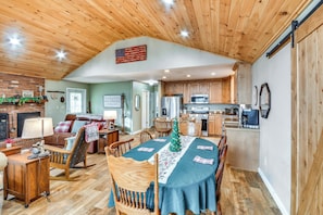 A cozy living room with a fireplace, a dining table with a Christmas tree, and wooden flooring.