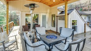 Eine überdachte Terrasse mit Sitzgelegenheit im Freien, einem Feuerkorb und Blick auf den umliegenden Wald.