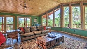 A spacious living room with a leather sofa, a wooden coffee table, and large windows offering a view of the outdoors. - < 1 Mi to Brian Head Resort: Mtn-View Gem w/ Deck (Brian Head)