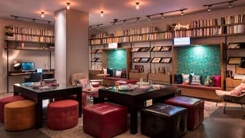 A modern library with bookshelves, a computer, and comfortable seating areas.