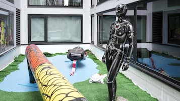 A room with a large window, a robotic figure, and a long, colorful object resembling a snake.