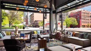 Un área de estar moderna con asientos, mesas y vistas a la ciudad.