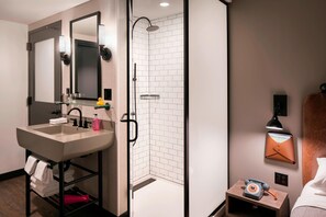 A modern bathroom with a sink, mirror, and shower.