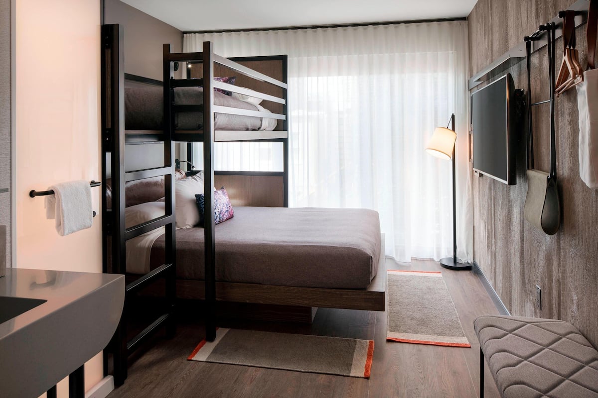 Habitación de hotel compacta con literas, televisión de pantalla plana, escritorio y zona de estar.