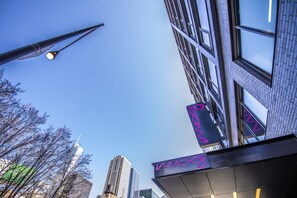 A modern building with a clear blue sky, a street lamp, and a neon sign.