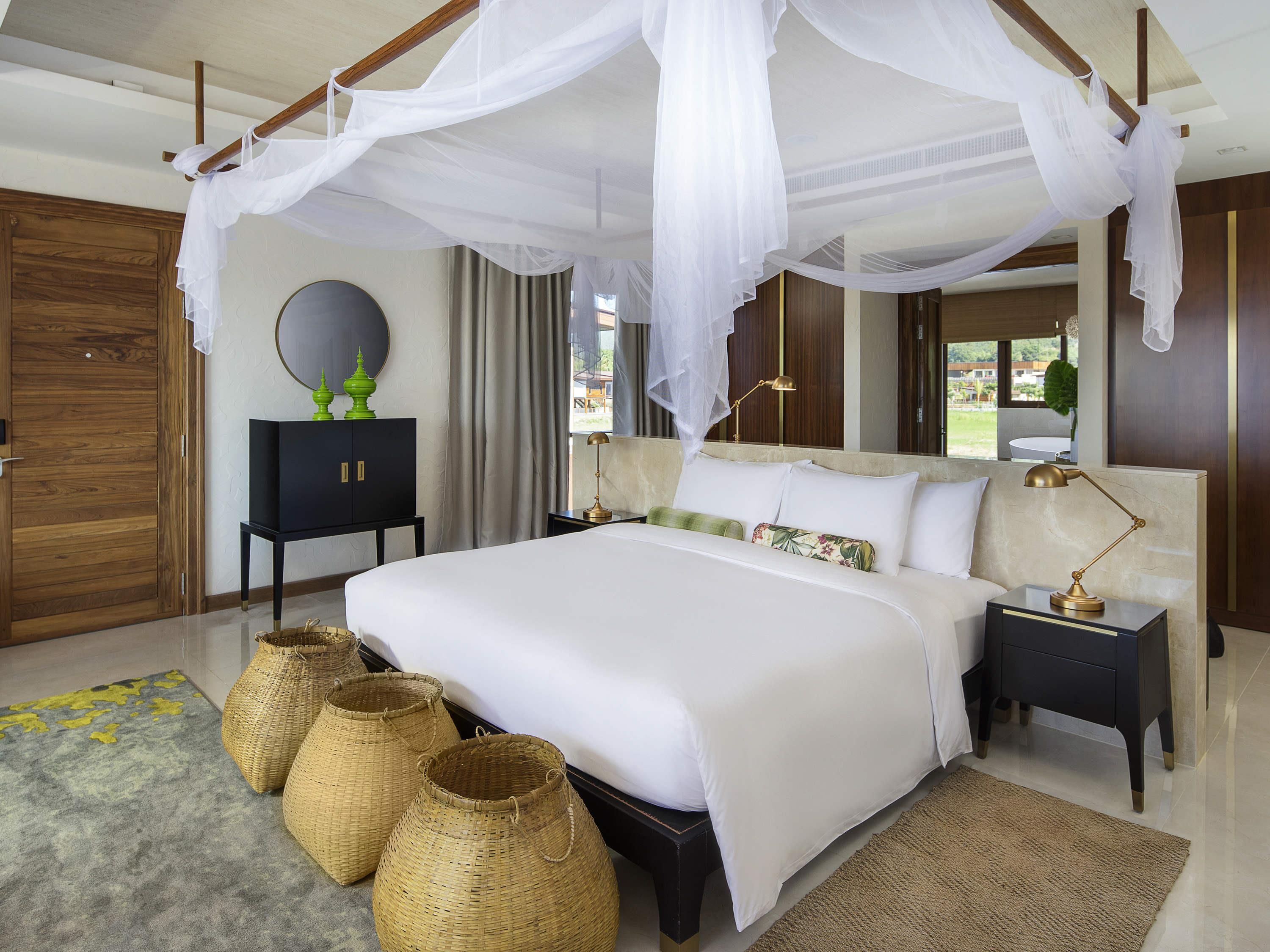 Un dormitorio con cama a dosel, mesitas de noche, armario y cestas decorativas.