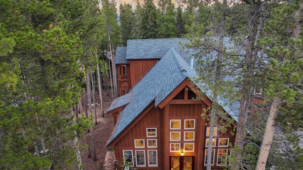 A cabin with a sloped roof surrounded by dense forest. - Sawmill Run Lodge: Pet-Friendly, Walk to Peak 8, Hot Tub, Grill, Shuttle (Breckenridge)