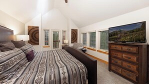 A bedroom with a large bed, a dresser, a television, and a window with a view of a mountainous landscape. - Sawmill Run Lodge: Pet-Friendly, Walk to Peak 8, Hot Tub, Grill, Shuttle (Breckenridge)