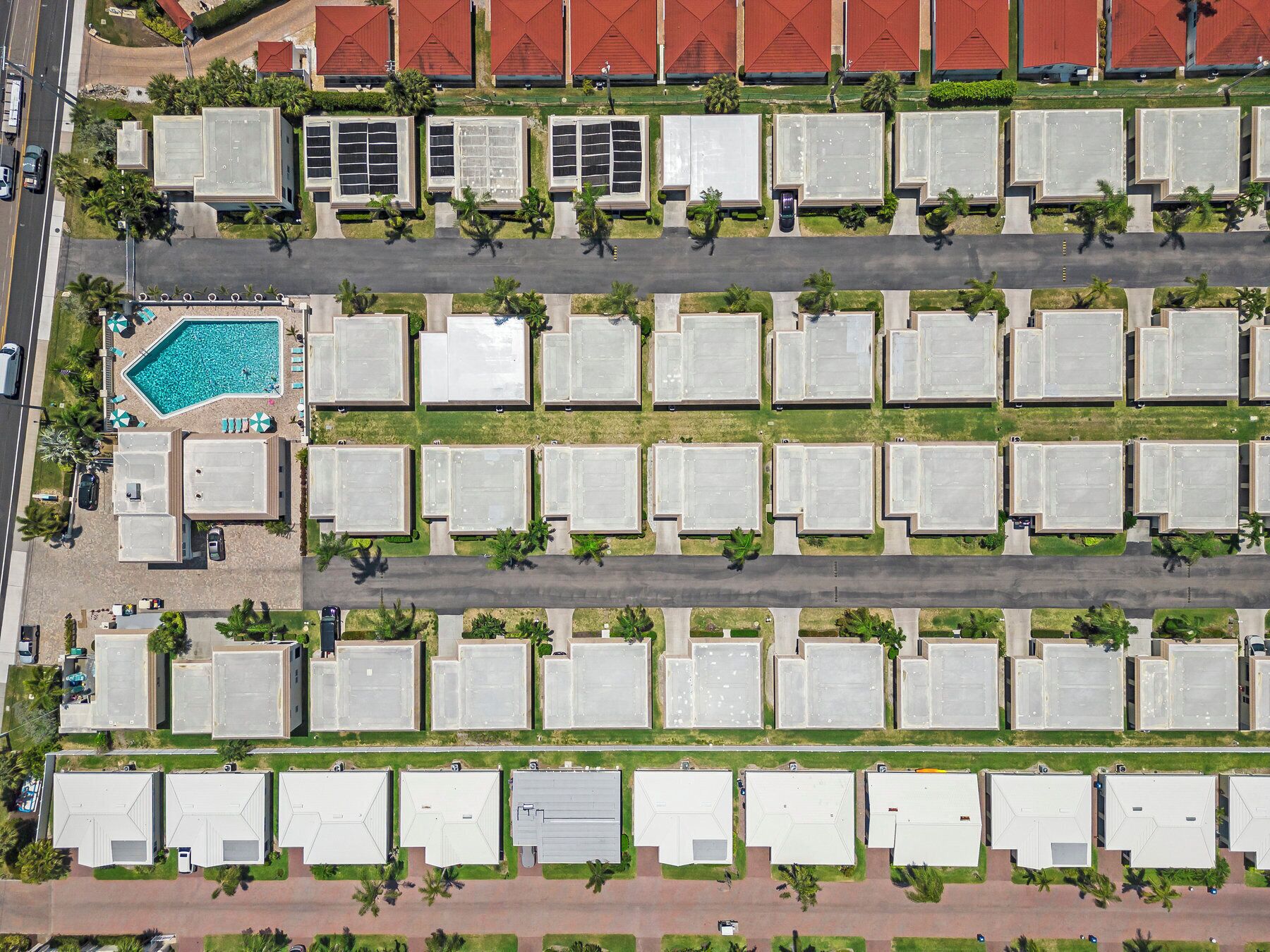 An aerial view of a hotel with multiple floors, each with a uniform row of rooms. There is a swimming pool on the ground floor.