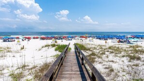 A beach with a wooden boardwalk leading to the shore, featuring beach umbrellas and sun loungers. - Gulf Front House in Orange Beach | Direct Beach Access | Pool | Sleeps 24 (Orange Beach)