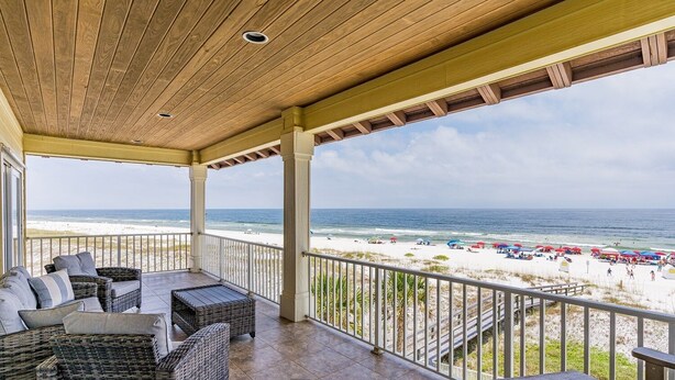 A covered balcony with wicker furniture, a view of the beach, and a clear sky. - Gulf Front House in Orange Beach | Direct Beach Access | Pool | Sleeps 24 (Orange Beach)