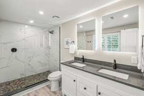 Ein modernes Badezimmer mit Duschkabine aus Glas, einer weißen Toilette und einem Waschtisch mit zwei Becken.