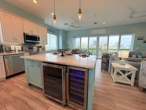 A kitchen with a central island, stainless steel appliances, and a dining area with a sofa and table.