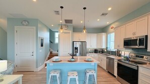 Cozinha moderna com ilha central, eletrodomésticos de aço inoxidável e esquema de cores em azul claro.