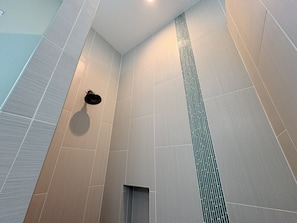 A modern bathroom with large tiled walls, a shower area, and a visible drain.