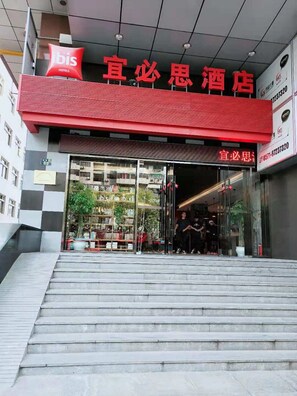 A hotel entrance with a red awning, glass doors, and a staircase leading up.