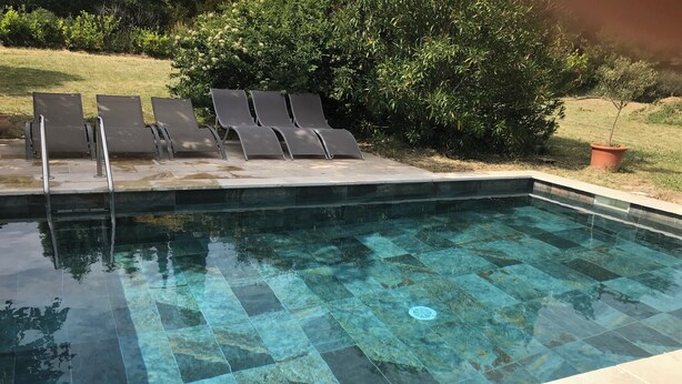 A clear swimming pool with a tiled edge, surrounded by a grassy area and a row of lounge chairs. - Vacation home in Luberon in the heart of Provence WIFI Free Fiber (Lauris)
