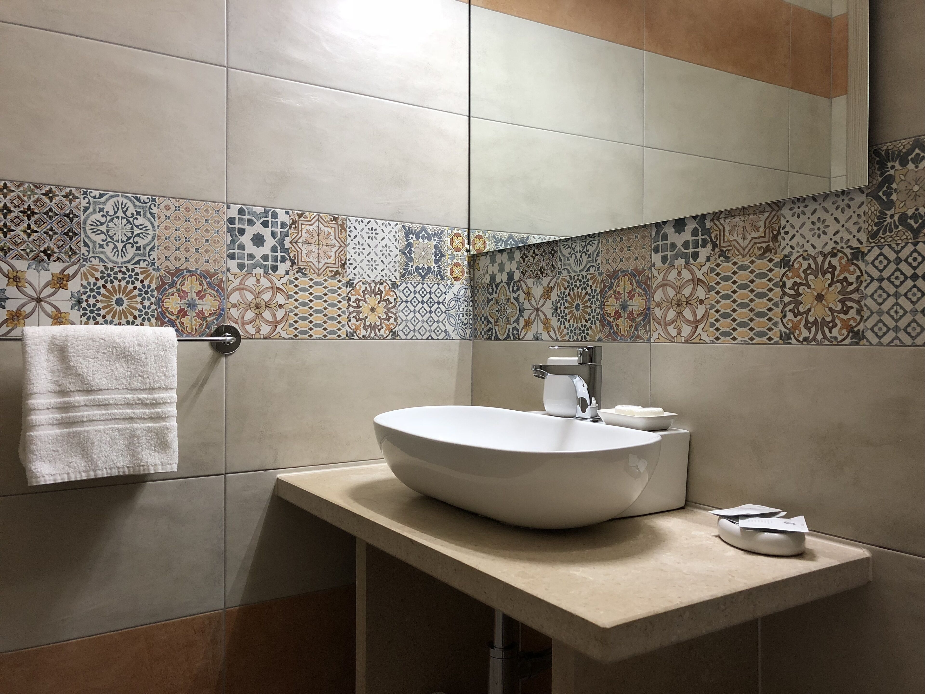 A modern bathroom with a large vessel sink, a towel rack, and a mirror.