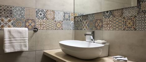 A modern bathroom with a large vessel sink, a towel rack, and a mirror.