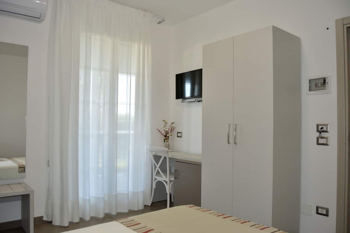 Un dormitorio con cama, escritorio, televisor y armario.